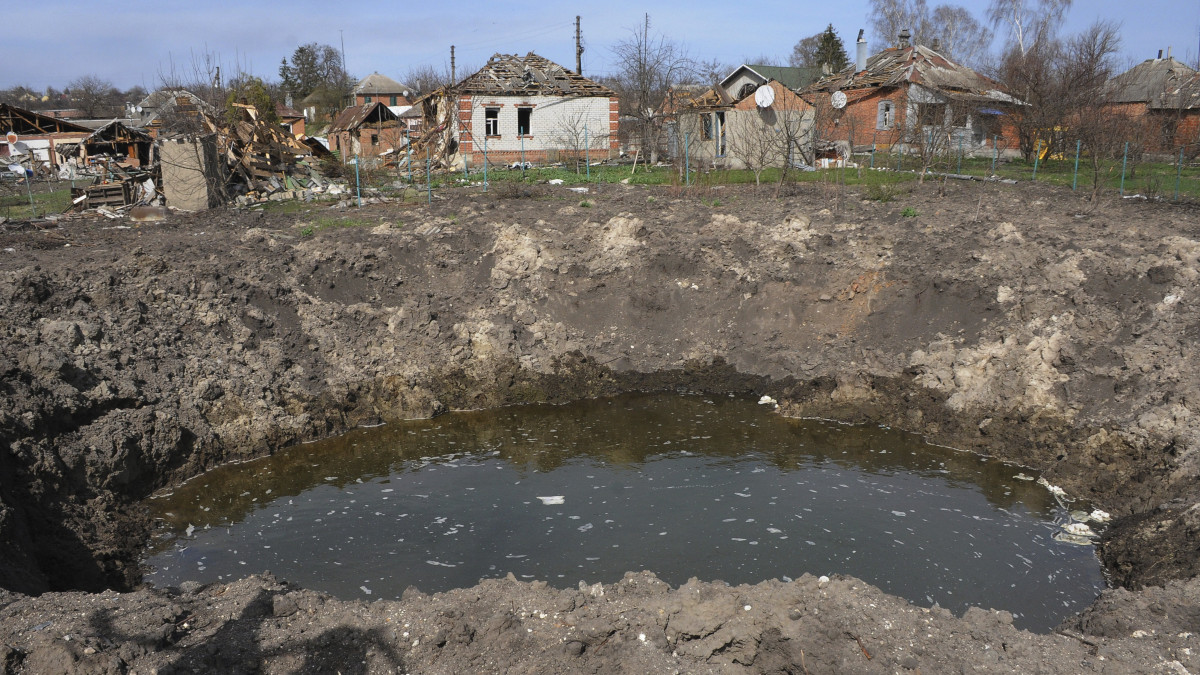 Robbanástól keletkezett kráter orosz tüzérségi támadásokban megrongált házak közelében a Harkiv közelében lévő Csuhuivban 2022. április 8-án.