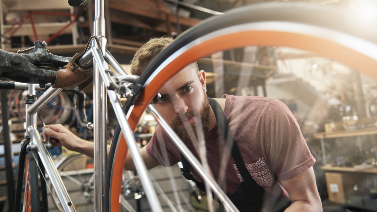 Shot of a handsome young bicycle mechanic working on a customerÂÂs bicycle