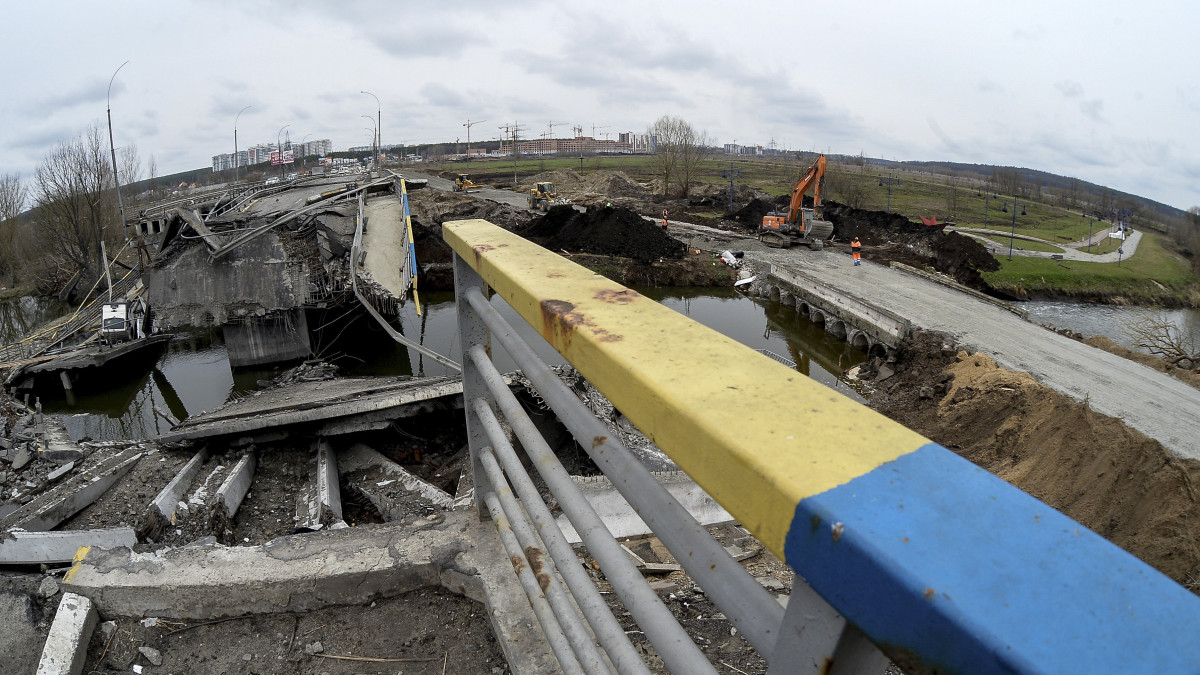 Új hidat (j) építenek az orosz támadások idején lerombolt híd mellett az ukrán hadsereg által visszafoglalt, Kijev közelében lévő Irpinyben 2022. április 10-én.