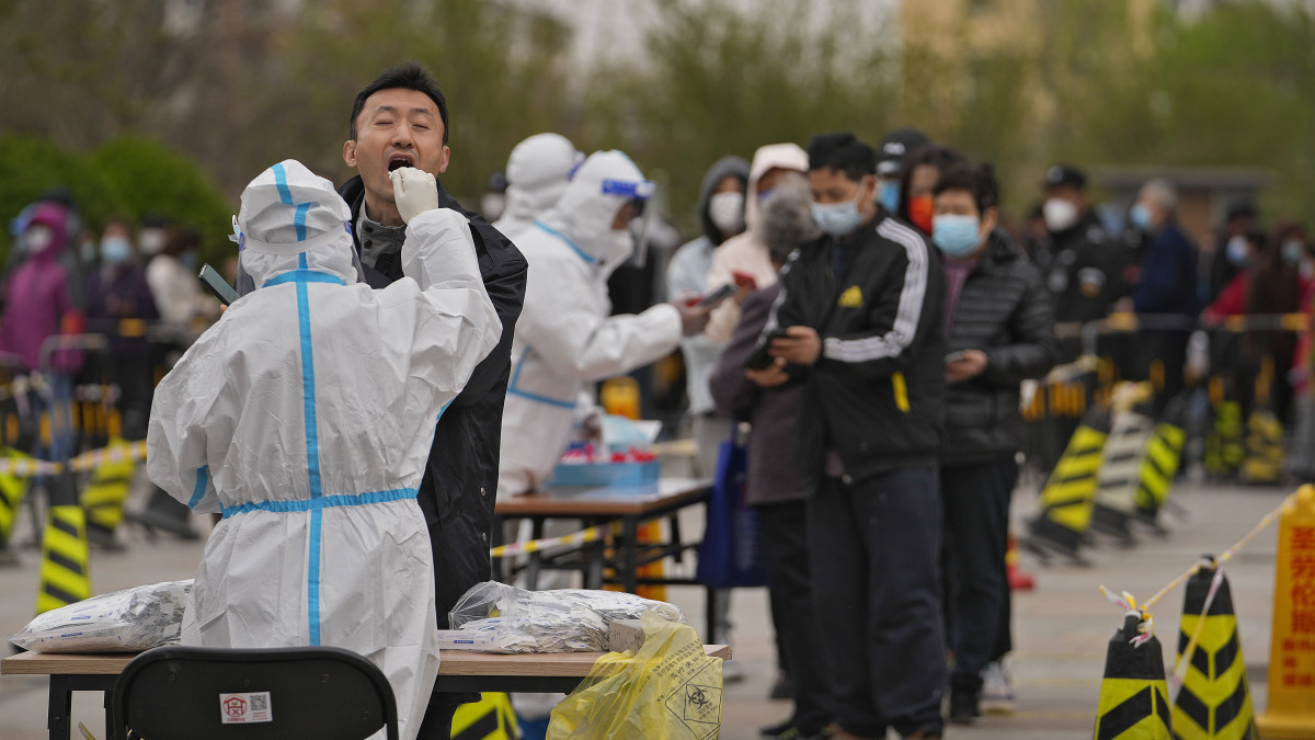 A koronavírus-járvány miatt védőruházatot viselő dolgozó mintát vesz koronavírus-teszteléshez Pekingben 2022. április 6-án.