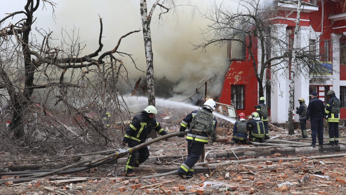 Tűzoltók oltják orosz támadásban megrongálódott lakóépület lángjait fékezik meg Harkivban 2022. április 12-én.