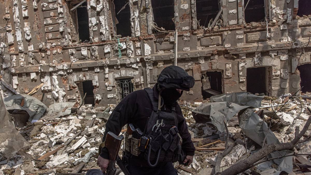 Ukrán katona orosz támadásban megsemmisült épületek romjai között Harkivban 2022. április 16-án.