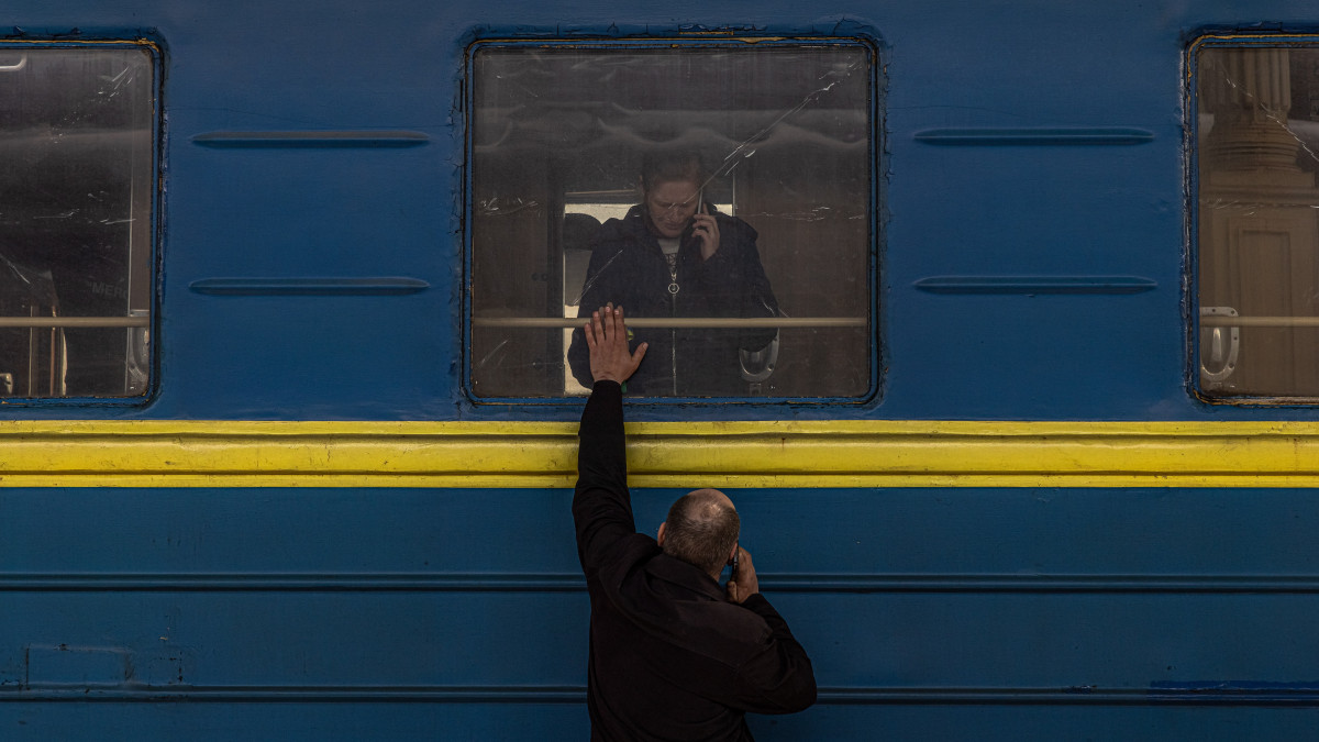 A városból távozó feleségétől és lányától búcsúzik egy ukrán férfi a harkivi vasútállomáson 2022. április 16-án.