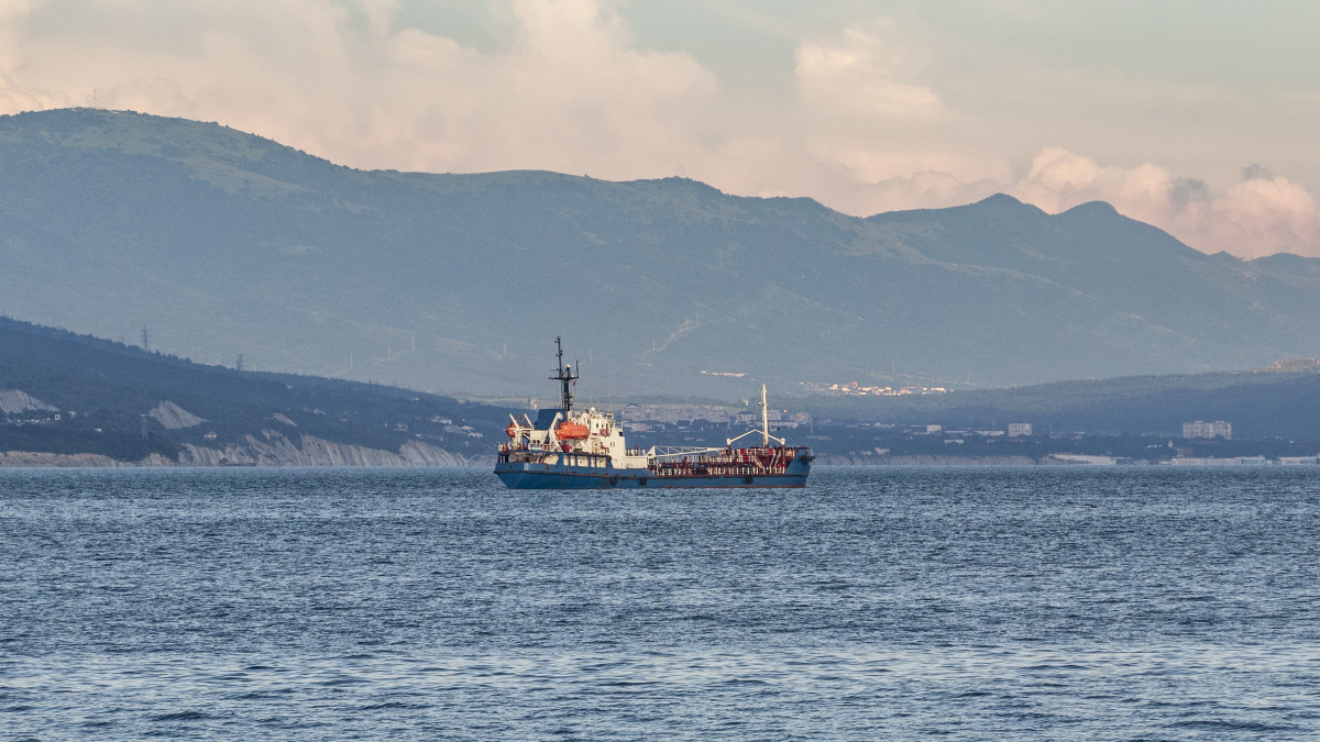 Fuel tanker or bunker ship sailing on water at mountains background