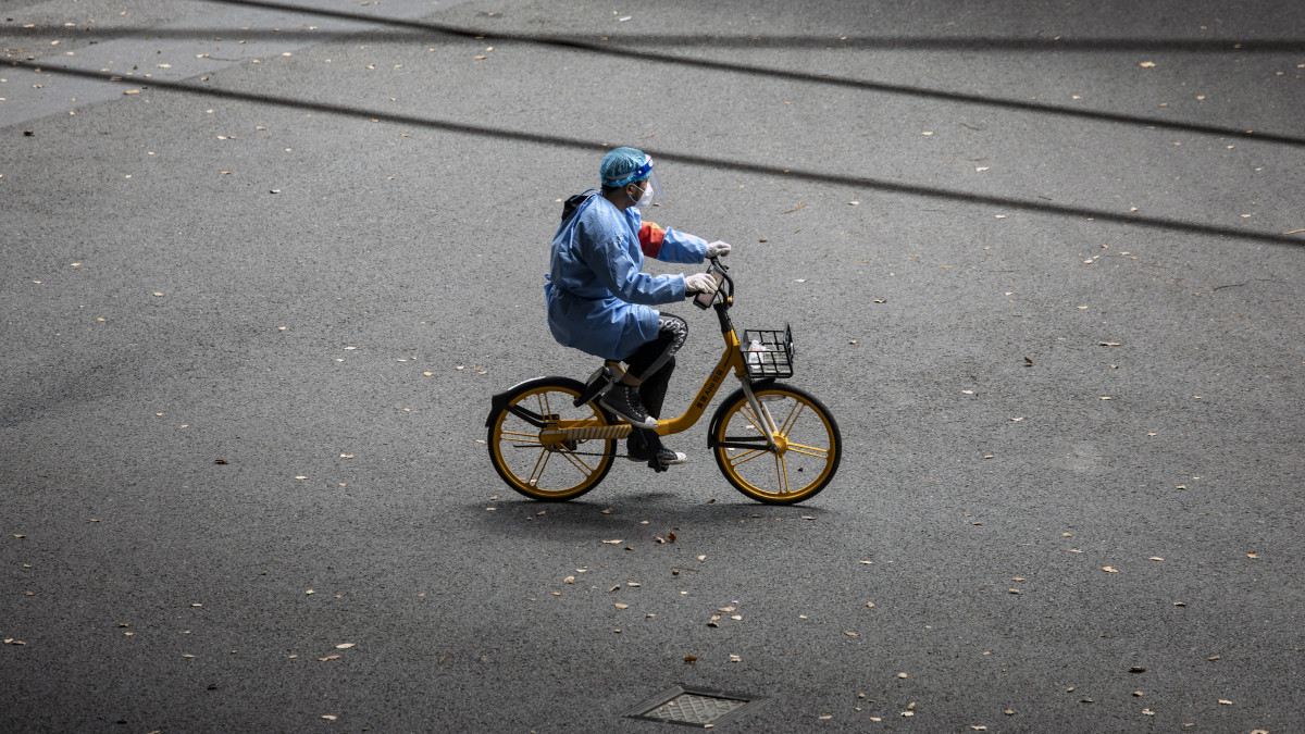 A worker in personal protective equipment (PPE) rides a bike along a road during a lockdown due to Covid-19 in Shanghai, China, on Monday, April 25, 2022. Shanghai, the epicenter of Chinas worst outbreak since Wuhan more than two years ago, reported 51 fatalities on Sunday, taking deaths in the current wave to 138. Source: Bloomberg