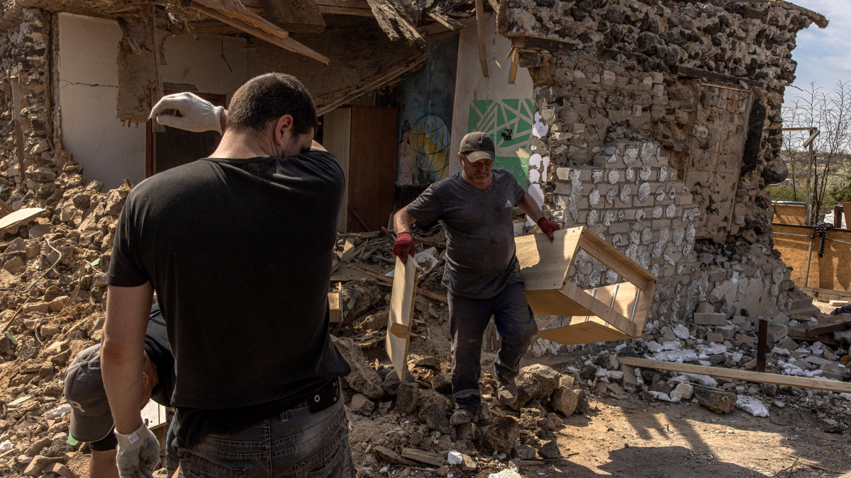 Helyi lakosok takarítják az előző napi orosz rakétatámadásban megrongálódott épületeket a dél-ukrajnai Zaporozzsjában 2022. április 29-én.