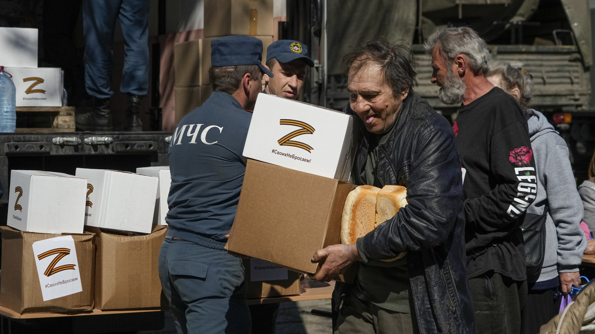 Helyi lakosok az önhatalmúlag kikiáltott Donyecki Népköztársaság katasztrófavédelmi minisztériuma által osztott élelmiszert viszik dobozokban a délkelet-ukrajnai Mariupolban 2022. április 29-én. A dobozokon az Ukrajna elleni háborúban az orosz hadsereg szimbólumává vált Z betű.
