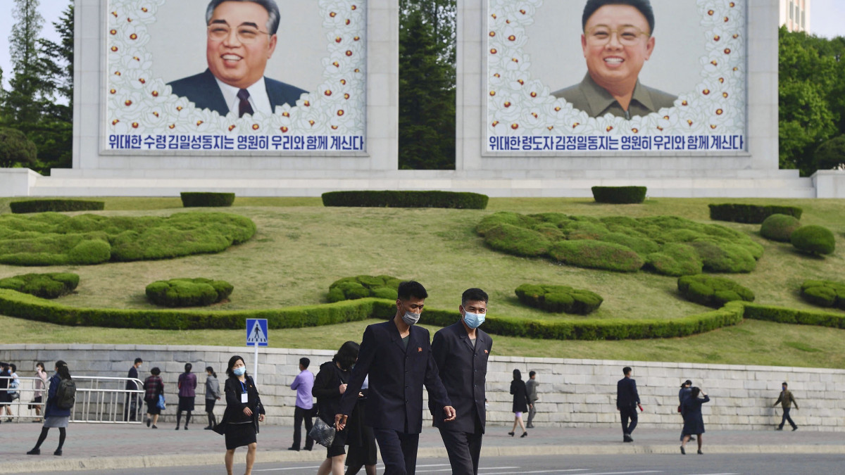 People wearing face masks walk by portraits of late North Korean leaders Kim Il Sung and Kim Jong Il in Pyongyang on May 6, 2022. North Koreas state-run media reported on May 12 that the country had detected the Omicron variant of the coronavirus from a sample collected in Pyongyang earlier in the month. (Photo by Kyodo News via Getty Images)