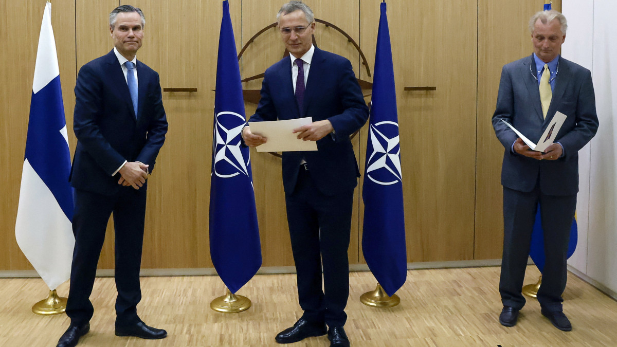 Jens Stoltenberg NATO-főtitkár (k) átveszi Klaus Korhonen finn (b), valamint Axel Wernhoff svéd NATO-nagykövettől az országuk hivatalos csatlakozási kérelméről szóló dokumentumokat a katonai szövetség brüsszeli székházában tartott ceremónián 2022. május 18-án.