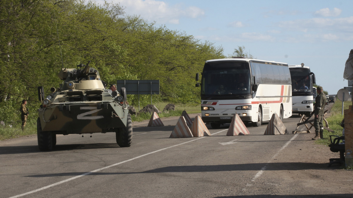 A mariupoli Azovsztal acélmű területéről evakuált ukrán katonákat szállító buszokat kísér egy orosz páncélozott jármű az önhatalmúlag kikiáltott Donyecki Népköztársaság ellenőrzése alatt álló Oljonivka börtönébe 2022. május 17-én. A nap folyamán több mint 260 ukrán harcos - sokan közülük sebesültek - hagyhatta el az acélmű területét.