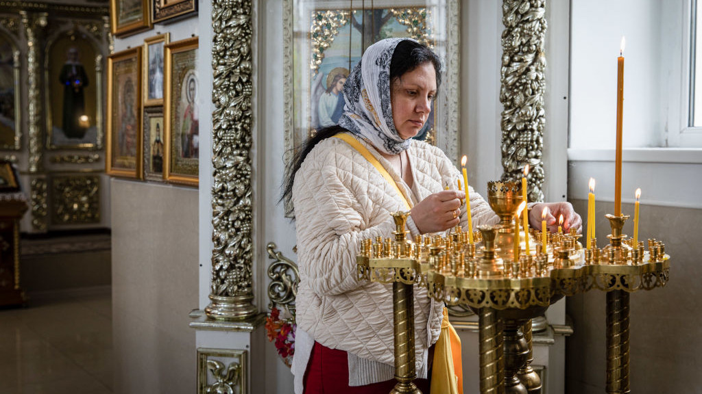 BAKHMUT, UKRAINE - 2022/05/22: A woman lights candles during the Sunday service in an Orthodox Monastery in Bakhmut, Donbas. Donetsk(Donbas) region is under heavy attack, as Ukraine and Russian forces contest the area. (Photo by Alex Chan/SOPA Images/LightRocket via Getty Images)