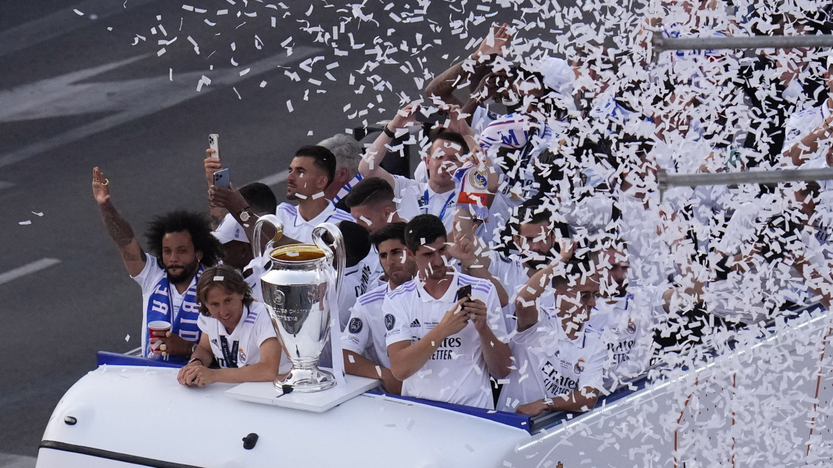 A Real Madrid játékosai egy nyitott tetejű buszon ünnepelnek a BL-trófeával a madridi városháza előtt 2022. május 29-én, egy nappal azután, hogy csapatuk 1-0-ra győzött a Liverpool FC ellen a labdarúgó Bajnokok Ligájának franciaországi döntőjében. A csúcstartó Real Madrid a 14. trófeáját szerezte meg a labdarúgás legrangosabb európai kupasorozatának döntőjében.