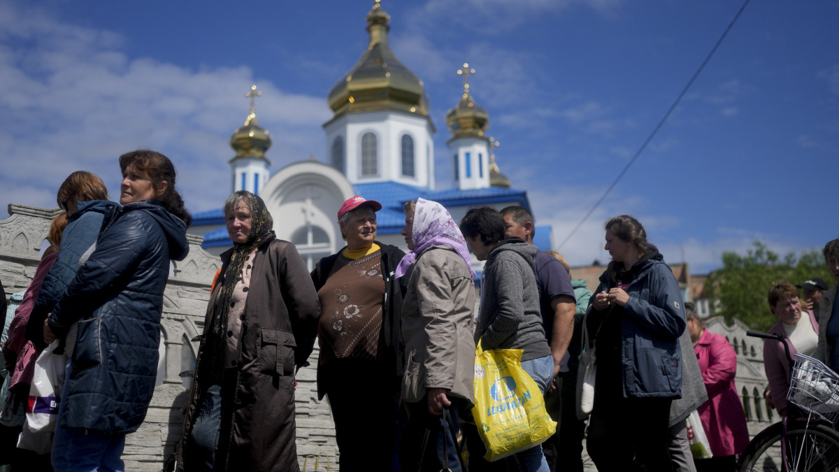 Ingyenes ruhaosztásra és élelmiszersegélyre várakoznak emberek egy templom előtt a Kijev közelében lévő Borodjankában 2022. május 31-én.