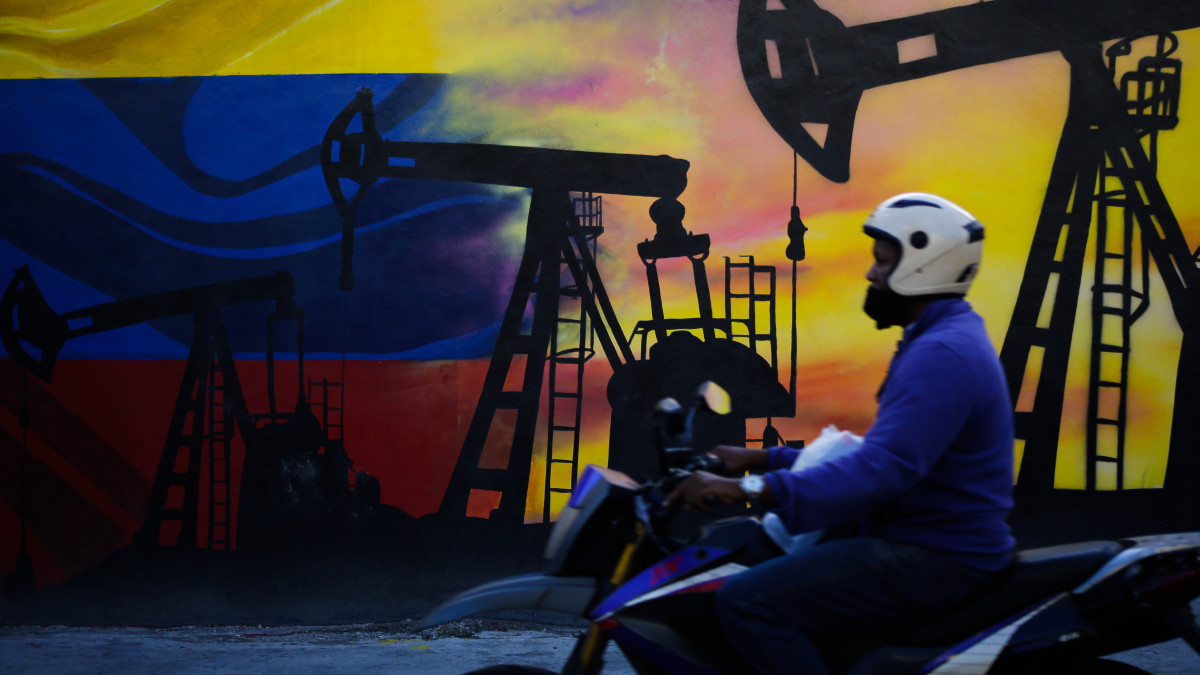 A motorcycle passes in front of an oil-themed mural in Caracas, Venezuela on May 9, 2022. (Photo by Javier Campos/NurPhoto via Getty Images)