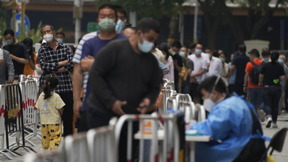 Koronavírus-tesztelésre váró emberek sorakoznak egy pekingi tesztállomás előtt 2022. június 13-án. A kínai fővárosban a hatóságok egy újabb tömeges tesztelést fognak végrehajtani, miután egy éjszakai szórakozóhely vendégei között több mint 160 új megbetegedést regisztráltak.