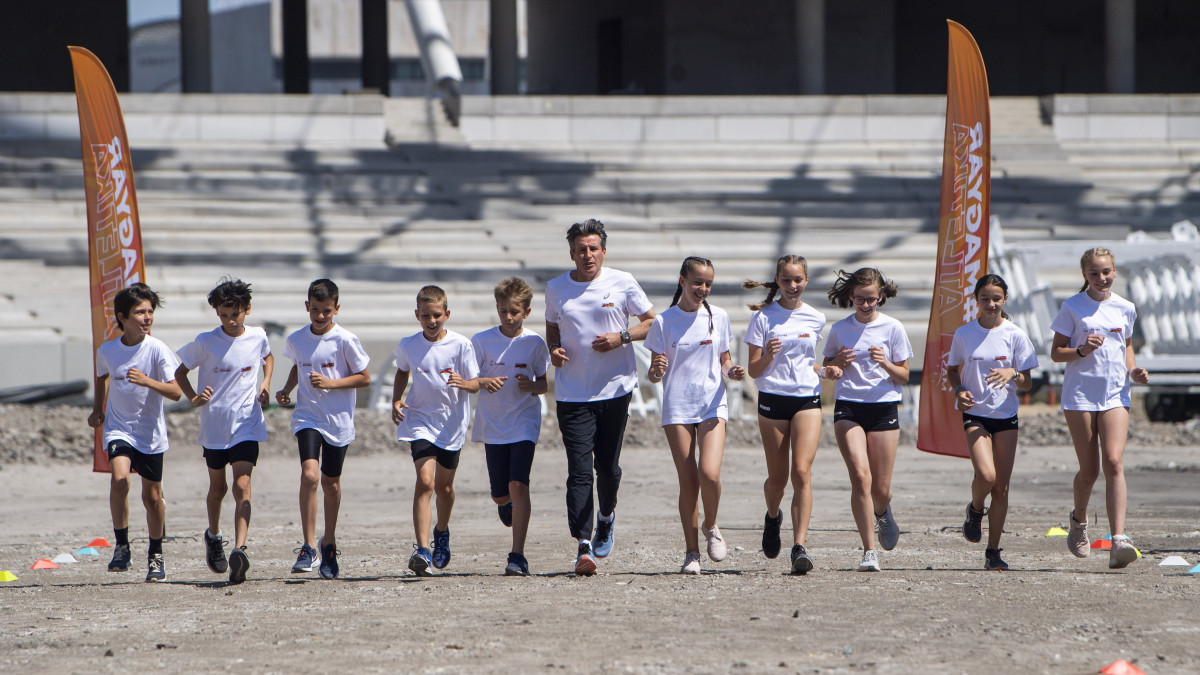 Sebastian Coe, a Nemzetközi Atlétikai Szövetség (IAAF) elnöke gyerekekkel fut az épülő Nemzeti Atlétikai Központban 2022. június 18-án. Látogatásán Sebastian Coe futotta az első métereket az új, még épülő Nemzeti Atlétikai Központban, ahol alig több mint egy év múlva az atlétikai világbajnokságot rendezik.