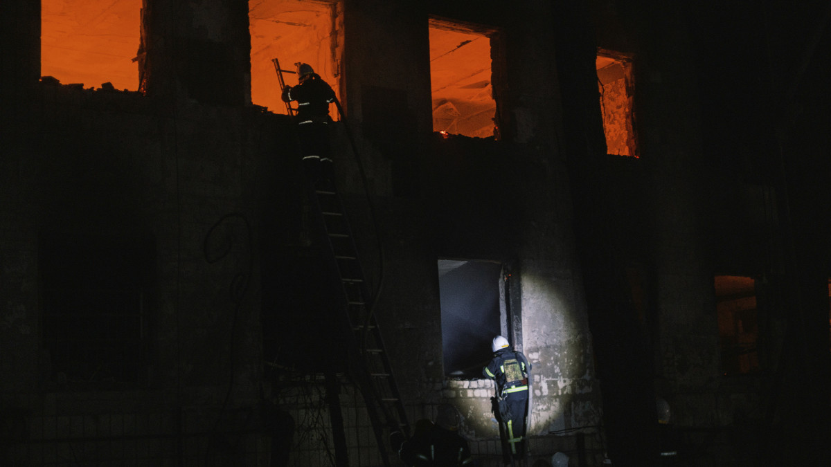 Lángoló épületnél tűzoltók a dél-ukrajnai Mikolajivban egy orosz tüzérségi támadás után, 2022. június 18-án.