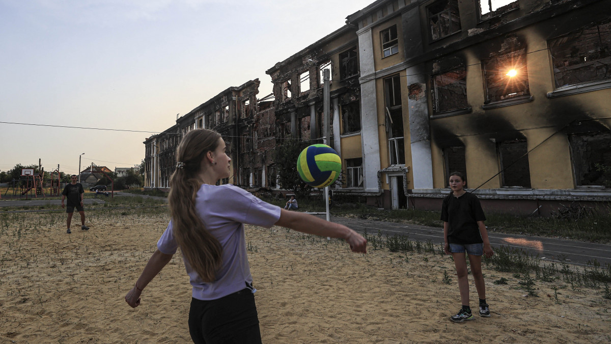 KHARKIV, UKRAINE - JUNE 10: Roman Tetelocko (40), a resident of Kharkiv is seen playing a volleyball with his daughter and her two friends at the sports field located in the playground of the school building number 134, as Russian attacks on Ukraine continue on June 10, 2022 in Kharkiv, Ukraine. In Kharkiv, citizens are trying to survive, despite the shelling that continues at night. In the city, where many points in the city center have fallen into ruins after the attacks, some Ukrainians, who come to the sports grounds in the playground of the school building number 134, play volleyball with their children. (Photo by Metin Aktas/Anadolu Agency via Getty Images)
