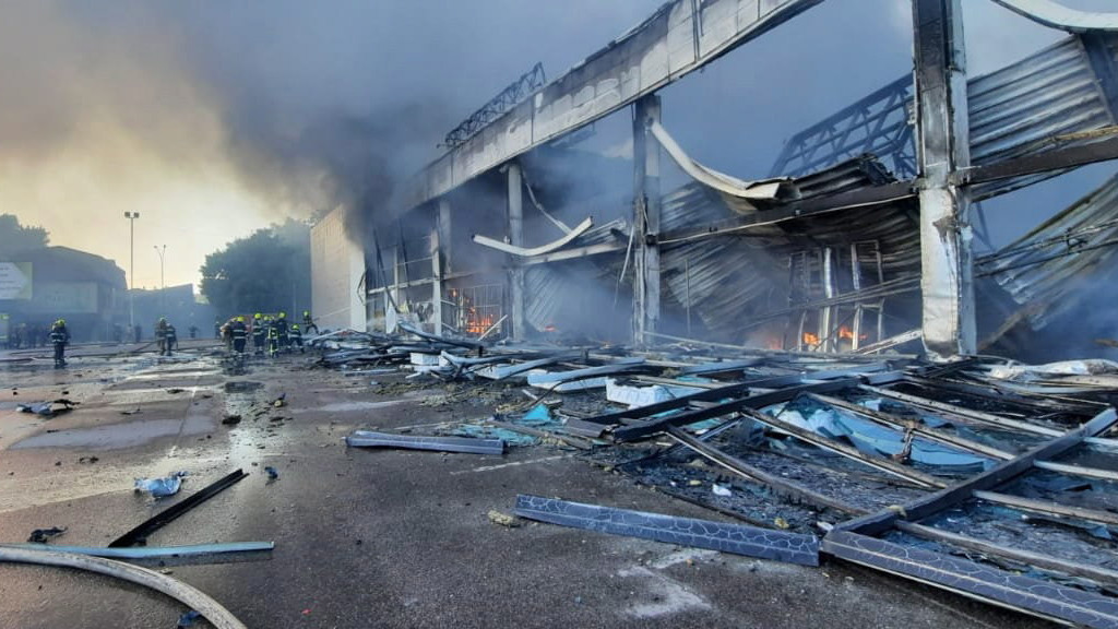 Az Ukrán Állami Katasztrófa-elhárító Szolgálat által közreadott képen egy bevásárlóközpont tüzét oltják tűzoltók az ukrajnai Kremencsukot érő orosz rakétatámadás után, 2022. június 27-én.