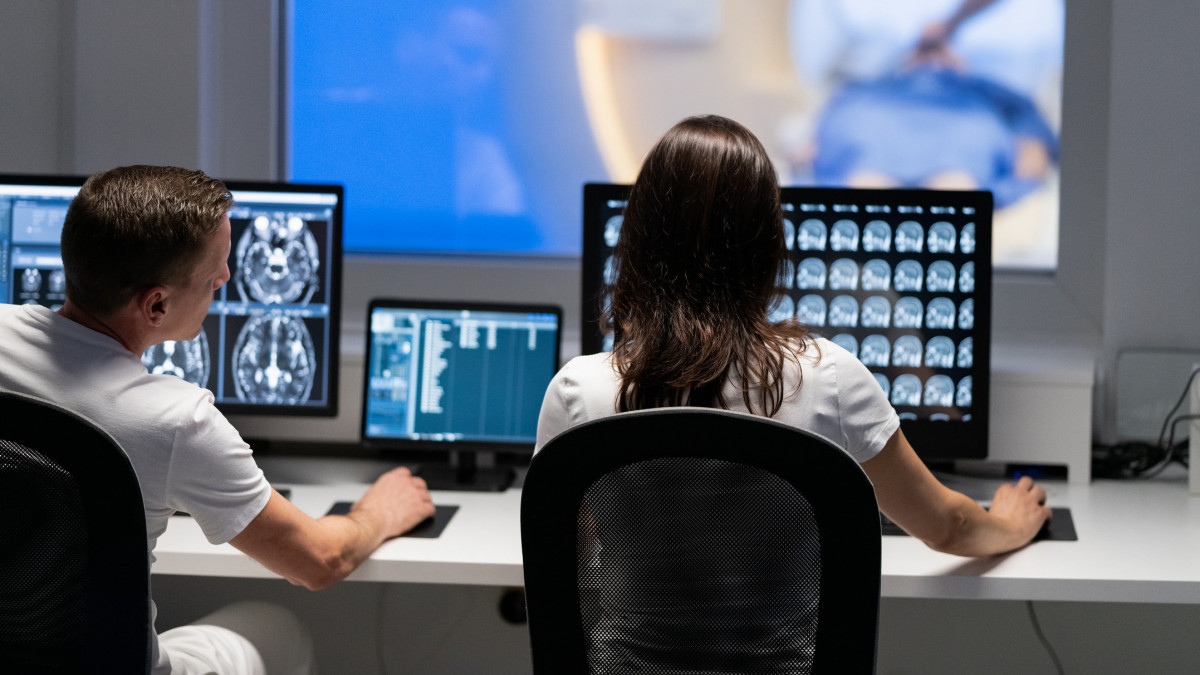Back view of two doctors radiologists analyzing MRI scan results. Magnetic resonance imaging technology in specialized medical clinic. Healthcare and medicine concept.