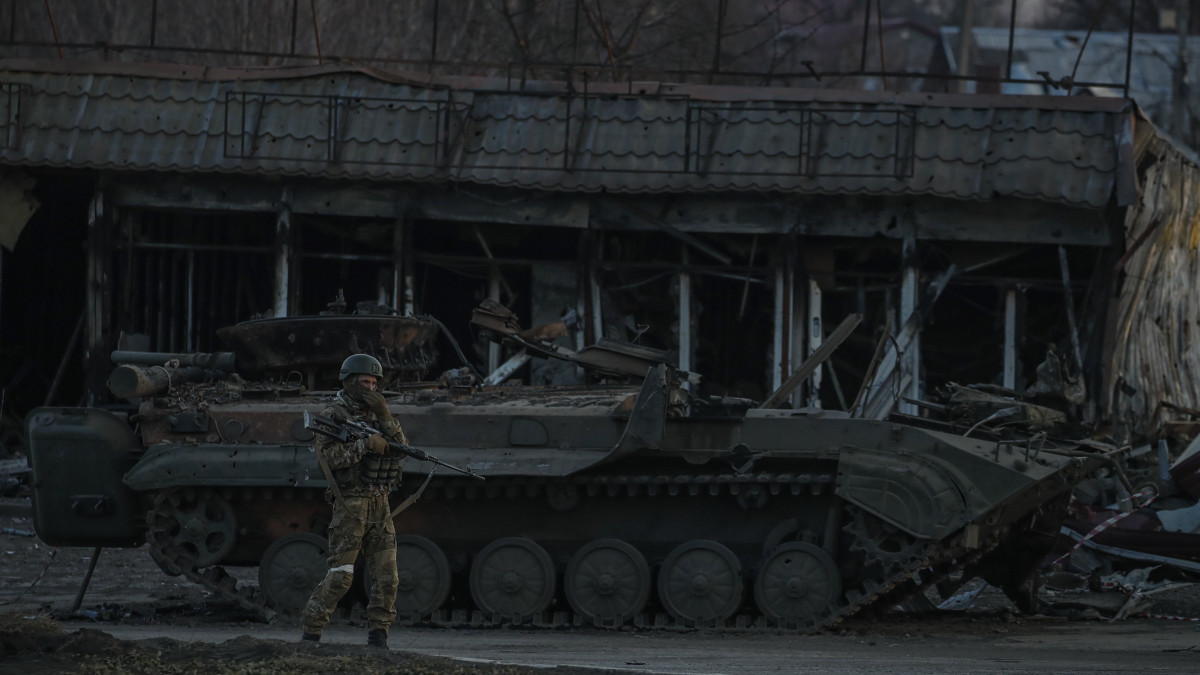 Orosz katona egy megsemmisített harcjármű mellett a Donyeck megye déli részén fekvő Volnovahában 2022. március 26-án. Az orosz csapatok által blokád alá vont kisváros lakóépületeinek 85 százaléka megsemmisült a harcokban. Vlagyimir Putyin orosz elnök február 24-én rendelte el katonai művelet végrehajtását Ukrajnában.