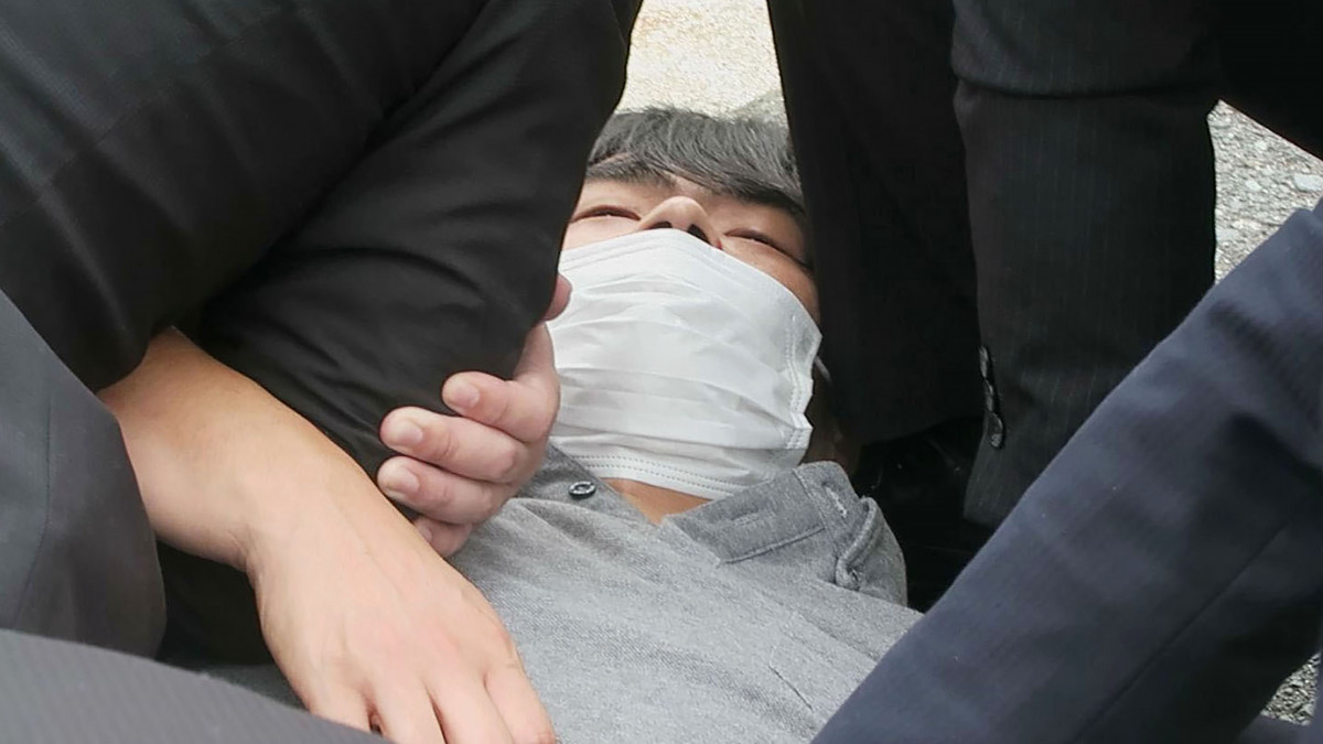A videófelvételről készült képen őrizetbe vesznek egy férfit, miután lövés érte Abe Sindzó korábbi japán miniszterelnököt egy választási kampányeseményen a közép-japáni Nara város Jamato-Szaidaidzsi vasútállomásánál 2022. július 8-án. Abe a lövéstől eszméletét vesztette, és kórházba szállították.