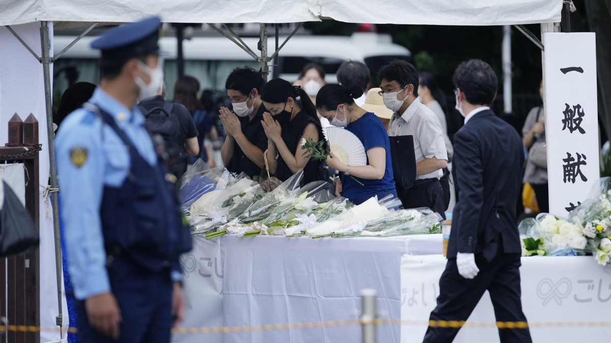 Virágot hagynak Abe Sindzó korábbi japán miniszterelnök tisztelői a tokiói Zodzsodzsi buddhista templom kertjében, mielőtt a meggyilkolt Abe koporsóját szállító halottaskocsi megérkezik a gyászszertartásra 2022. július 12-én. A 67 éves politikust július 8-án a Liberális Demokrata Párt választási kampányrendezvényén lőtték le beszéde közben a Japán középső részén fekvő Narában.