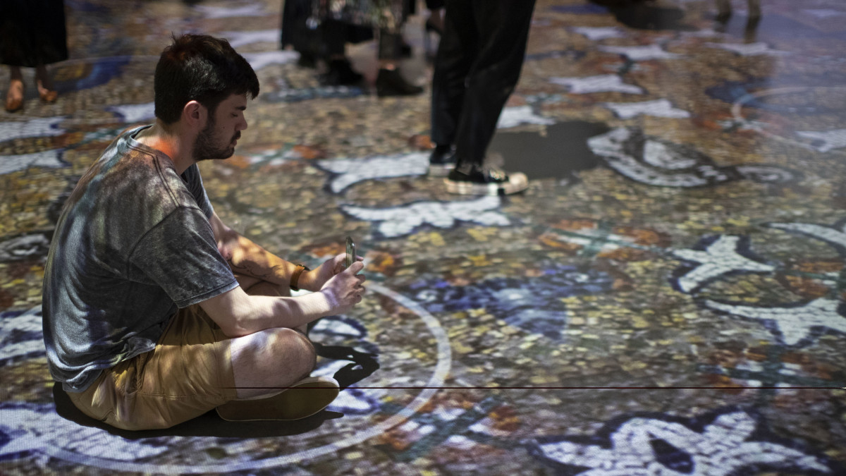 Látogatók a Gustav Klimt osztrák festőművész (1862-1918) alkotásaiból nyílt digitális művészeti kiállításon Bostonban 2022. április 14-én. A kiállítótermekben projektor vetíti a padlóra, a mennyezetre és a falakra Klimt alkotásait térbeli hangosítás mellett. A különleges élményt és látványt egyedi multimédiás eszközök biztosítják a tárlaton.