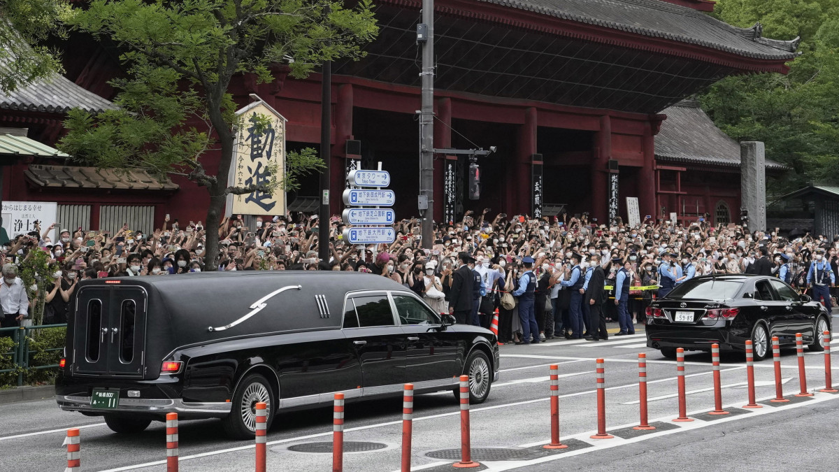 A meggyilkolt Abe Sindzó korábbi japán miniszterelnök koporsóját szállító halottaskocsi (b) elhagyja a tokiói Zodzsodzsi buddhista templomot a gyászszertartás végén 2022. július 12-én. A 67 éves politikust július 8-án a Liberális Demokrata Párt választási kampányrendezvényén lőtték le beszéde közben a Japán középső részén fekvő Narában.