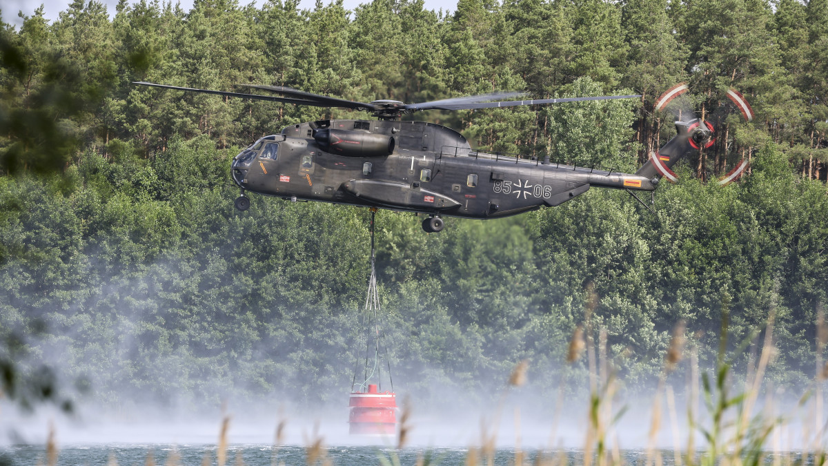 Erdőtűz oltásához vesz fel vizet a német hadsereg Bell CH-53-as tűzoltó helikoptere a kelet-németországi Falkenberg környékén 2022. július 26-án.