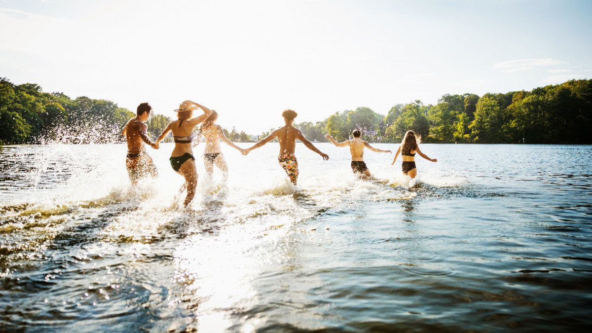 A group of friends wading into lake together in the afternoon summer sun.