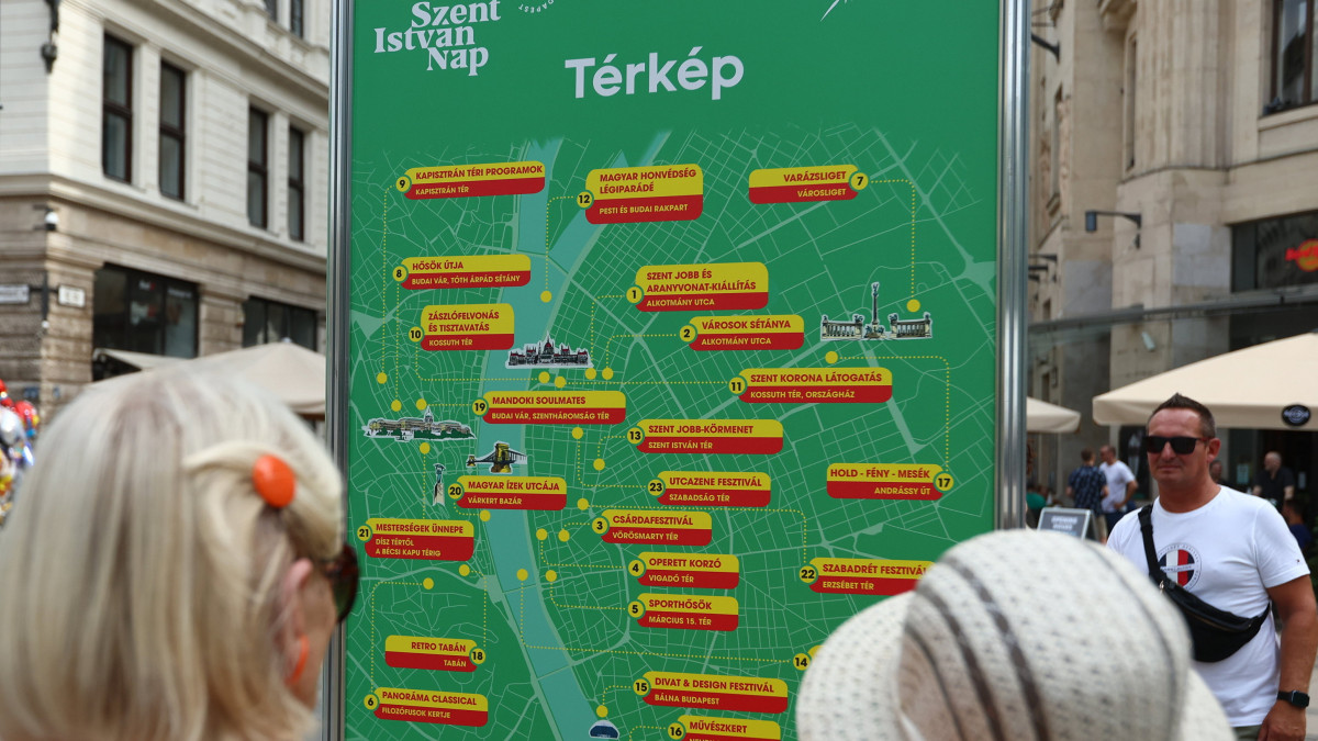 Érdeklődők a Szent István-napi programsorozat helyszíneit ismertető térképet nézik a fővárosi Vörösmarty téren 2022. augusztus 19-én.