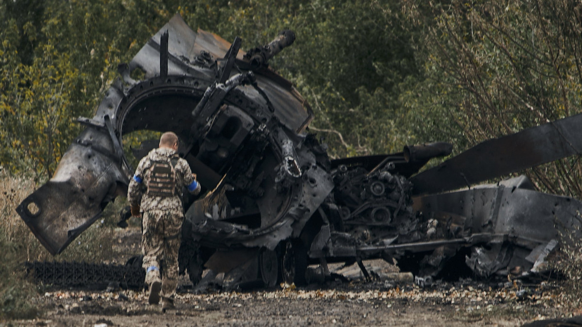 Orosz harckocsi roncsa mellett ukrán katona az ukrán hadsereg által frissen visszafoglalt területen, a Harkivi területen fekvő Balaklejába vezető úton 2022. szeptember 11-én.