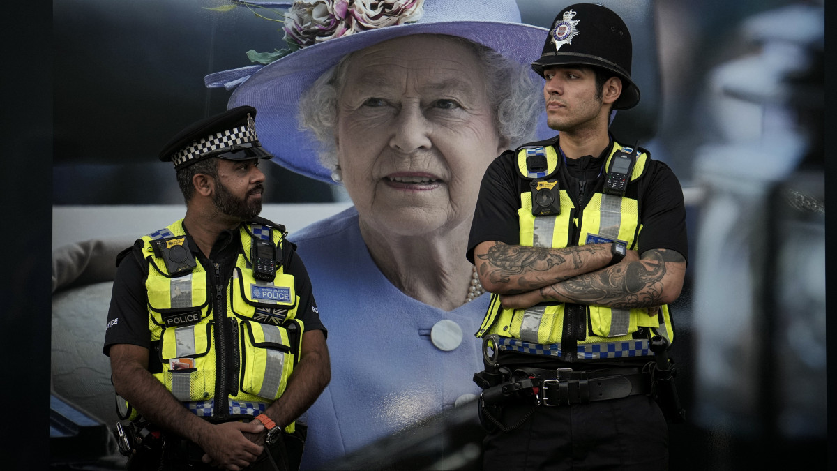 II. Erzsébet királynő képe előtt őrködik két londoni rendőr 2022. szeptember 16-án. A szeptember 8-án, 96 éves korában, uralkodásának 71. évében elhunyt királynő négy napra, a szeptember 19-i temetésig van felravatalozva a londoni Westminster-csarnokban.
