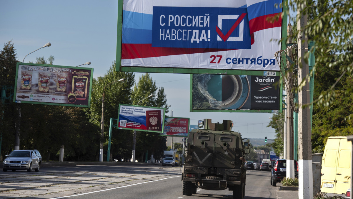 Örökre Oroszországgal jelentésű óriásplakát alatt hajt el egy katonai jármű a kelet-ukrajnai Luhanszkban 2022. szeptember 22-én. A vegyes lakosságú területeken  szeptember 23. és 27. között népszavazást tartanak a hovatartozásról. A referendum az oroszbarát szakadár Donyecki és Luhanszki Népköztársaságban, valamint az orosz megszállás alá került Herszon és Zaporizzsja ukrán megyékben élőket érinti.