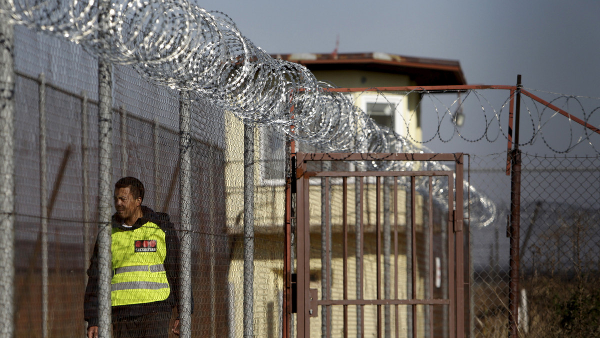 A security guard walks along a fence topped with barbed and razor wire in a facility for a detention of foreigners in the village of Drahonice, western Czech Republic, October 2, 2015. The Refugee Facilities Administration of the Interior Ministry will open this detention centre on October 5, 2015, to house incoming migrants.    REUTERS/David W Cerny