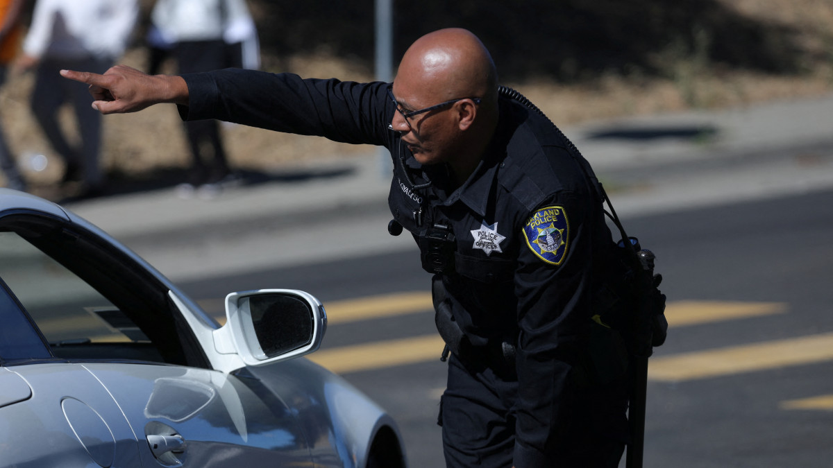 A police officer directs traffic at a road closure after a shooting near a school in Oakland, California, U.S. September 28, 2022. REUTERS/Nathan Frandino