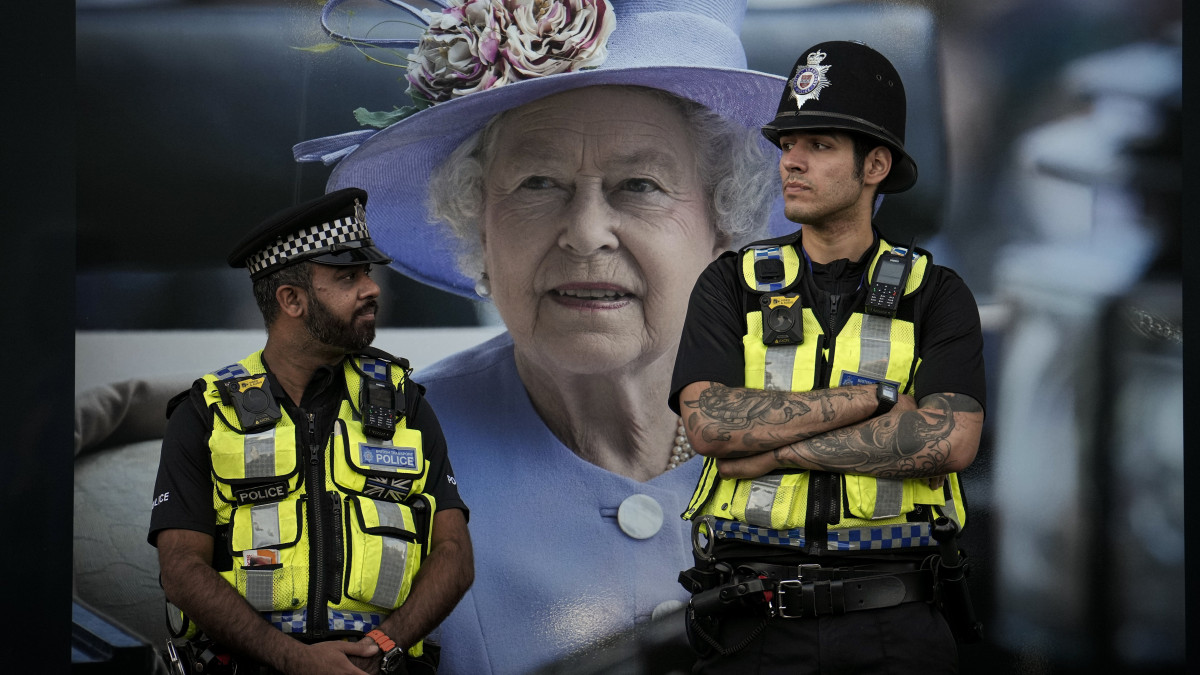 II. Erzsébet királynő képe előtt őrködik két londoni rendőr 2022. szeptember 16-án. A szeptember 8-án, 96 éves korában, uralkodásának 71. évében elhunyt királynő négy napra, a szeptember 19-i temetésig van felravatalozva a londoni Westminster-csarnokban.