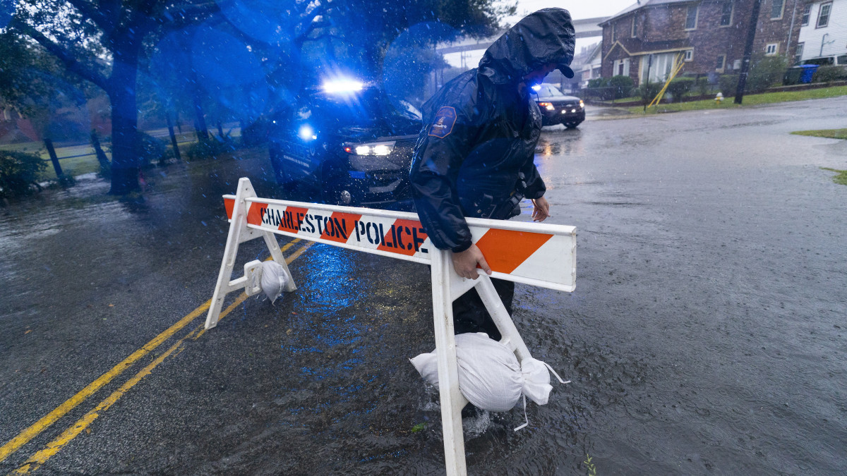 Hatósági útakadályt helyez ki egy rendőr az Ian hurrikán által elárasztott autóutak egyikén a dél-karolinai Charlestonban 2022. szeptember 30-án. Az amerikai meteorológiai szolgálat életveszélyes partvidéki áradásokra és tengeri árhullámokra figyelmeztet Floridától Georgia államon keresztül Dél- és Észak-Karolináig.