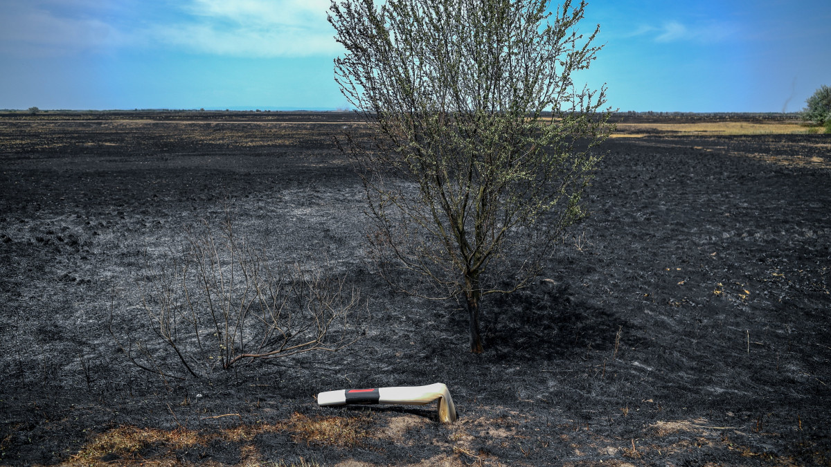 Megolvadt útjelző oszlop a szárazság és a meleg időjárás miatt leégett területen Tiszafüred-Kócsújfalu határában 2022. július 22-én. Július 20-án a Hortobágyi Nemzeti Park területén mintegy kétszáz hektáron égett foltokban az erdő aljnövényzete és nádas-bozótos részek. A tűzoltók megfékezték a lángokat.