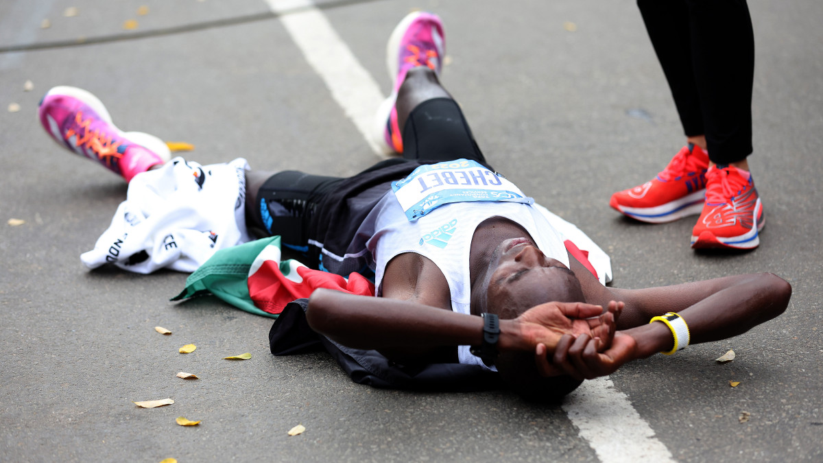 NEW YORK, NEW YORK - NOVEMBER 06:  Evans Chebet of Kenya collapses after crosses the finish line to win the TCS 2022 New York City Marathon as Mayor Eric Adams looks on on November 06, 2022 in New York City. (Photo by Jamie Squire/Getty Images)