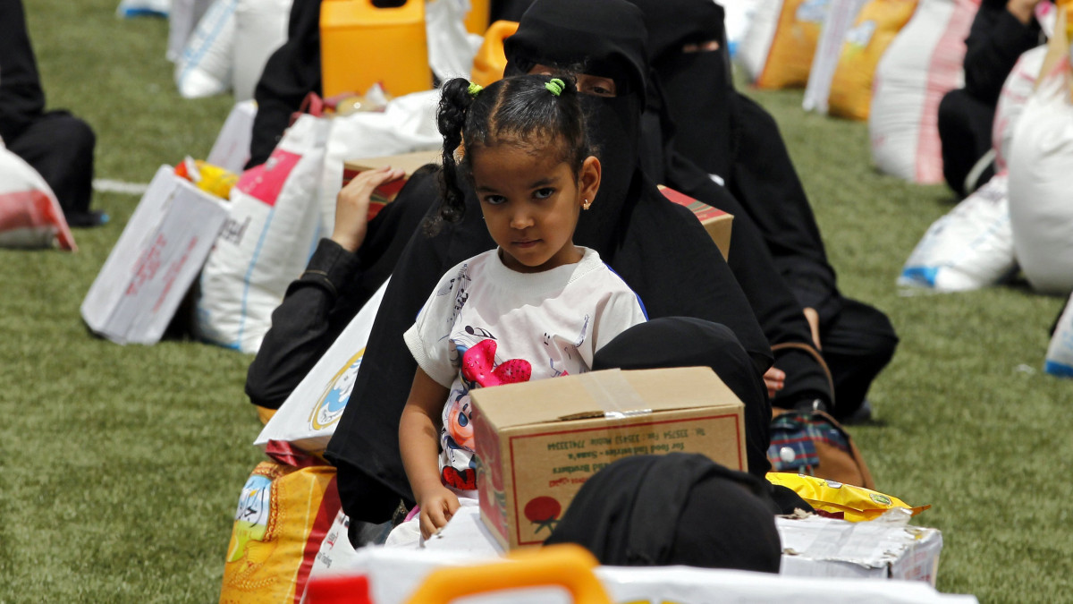 Szanaa, 2017. június 20.Egy kislány és édesanyja várakozik a kuvaiti kormánytól kapott élelmiszersegély-adagjuk mögött a háborús válság sújtotta jemeni fővárosban, Szanaában 2017. június 19-én. Az ENSZ Világélelmezési Programjának (WFP) becslése szerint Jemenben több mint 14 millió embert fenyeget közvetlen veszély a súlyos élelmiszerhiány miatt.  (MTI/EPA/Jahja Arhab)