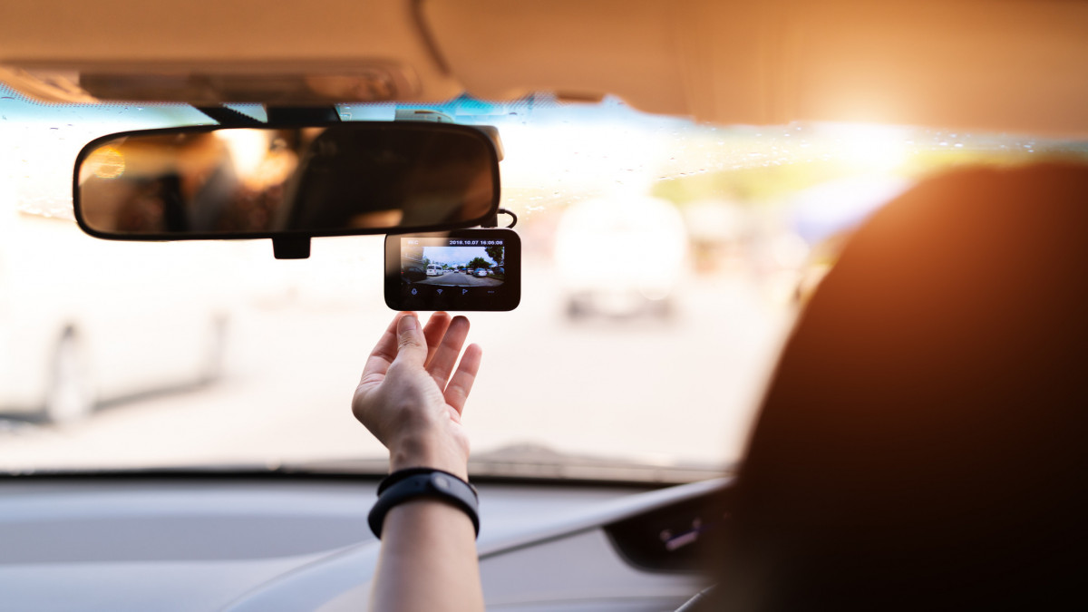 Front camera car recorder, woman set video recorder next to a rear view mirror
