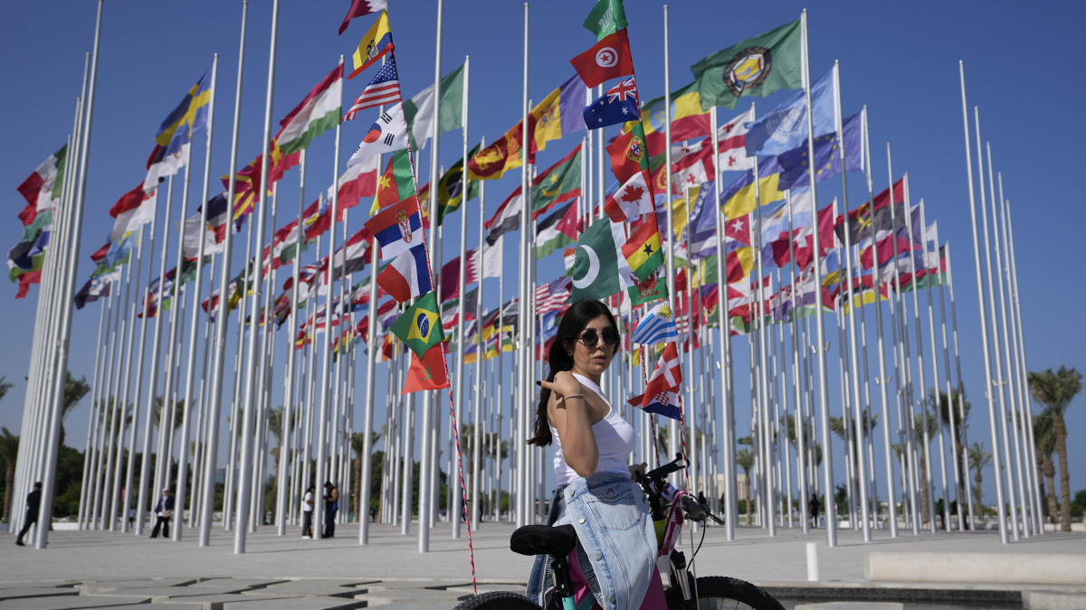 A 2022-es katari labdarúgó-világbajnokságon részt vevő országok zászlai előtt egy nő a katari fővárosban, Dohában, a zászlók terén 2022. november 11-én, kilenc nappal a Katar-Ecuador nyitómérkőzés előtt.
