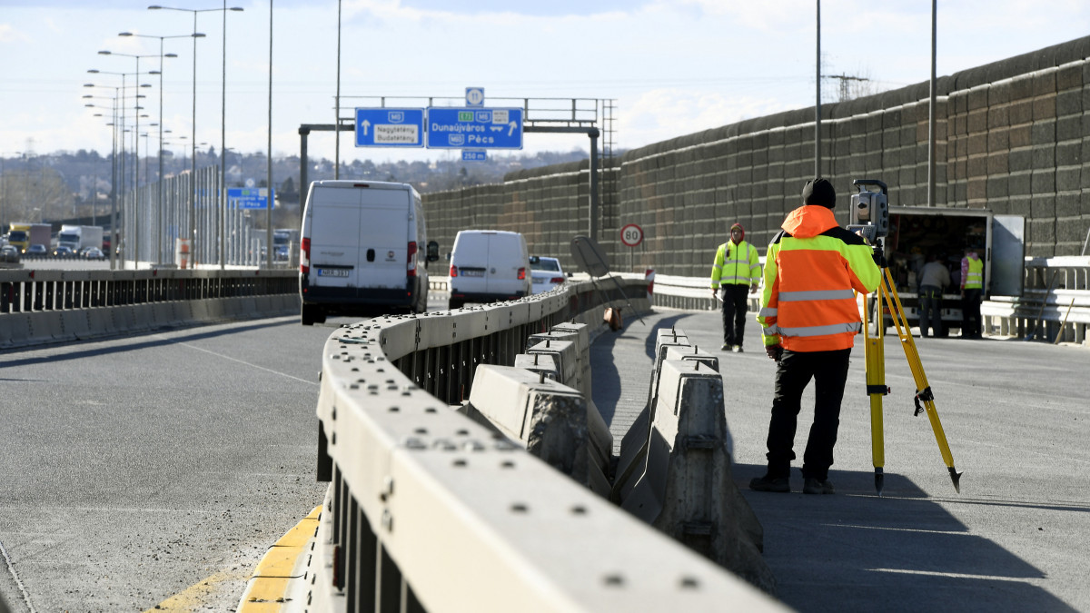 Munkások az M0-s autóút déli szakaszán, az M6-os kihajtójánál 2019. március 5-én. Április elejétől megkezdődik az M0 autóút déli szektorának felújítása, az 1-es főút és az M5-ös sztráda közötti szakaszon új forgalmi rend lép életbe.