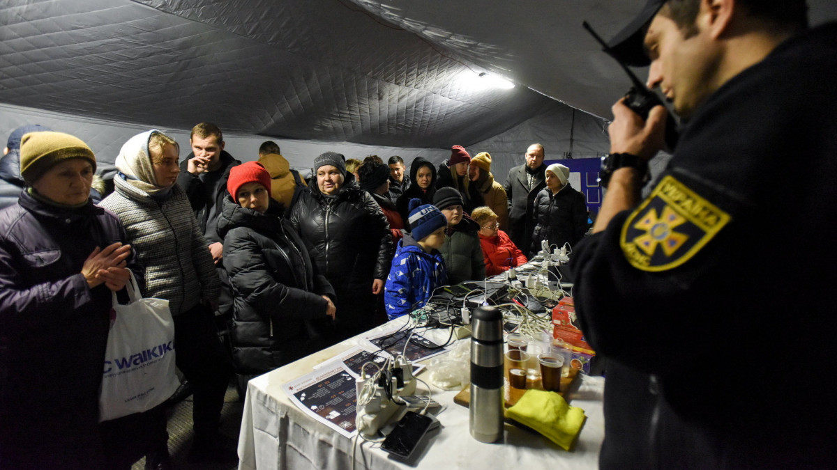 Elektronkus eszközeiket töltik fel árammal az emberek egy kijevi melegedőponton, amikor az orosz rakétatámadások miatt áramszünet van a kijevi lakások nagy részében 2022. november 24-én.