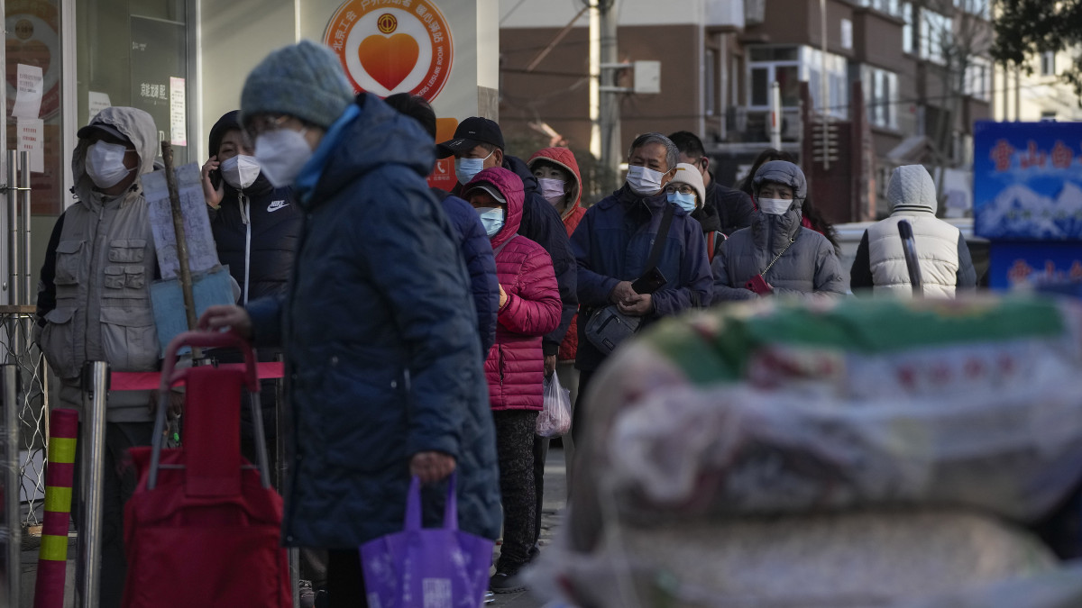 Egy újranyitott pekingi bevásárlóközpont előtt várakoznak emberek 2022. december elsején. Kína enyhített a koronavírus-járványra vonatkozó korlátozásokon, több város feloldotta a kerületi zárlatokat, és engedélyezte az üzletek újbóli megnyitását. Az enyhítésre annak ellenére került sor, hogy a napi esetszám rekord közelben mozog és az egyre szigorúbb rendeletek miatt országszerte tüntetések törtek ki.