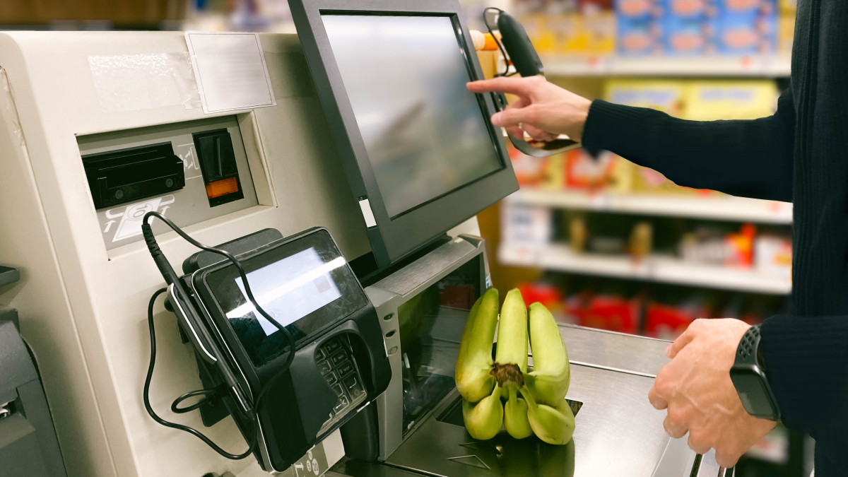 Close-up of unrecognizable man purchasing bananas at self-checkout kiosk in grocery store
