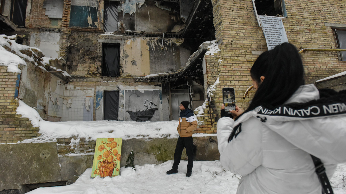 A 2022. december 3-i képen Banksy brit graffitiművész stencilképét fotózza egy nő egy szétbombázott lakóépületnél a Kijev megyei Horenkában. Az ismeretlen személyazonosságú politikai aktivista novemberben több ukrán településen is készített szatírikus üzenetű falfestményt. Banksy társadalmi mondanivalójú alkotásai számos országban feltűntek az utóbbi években.