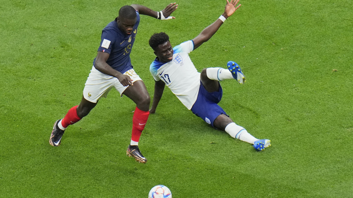 A francia Dayot Upamecano (b) és az angol Bukayo Saka küzd a labdáért a katari labdarúgó-világbajnokság Anglia-Franciaország negyeddöntő mérkőzésén az al-hori al-Bajt Stadionban 2022. december 10-én.